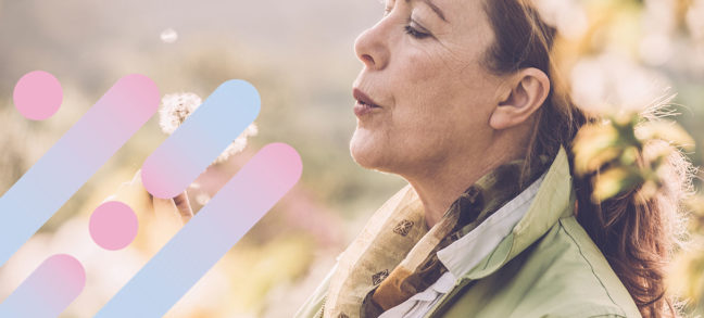 Woman outside blowing a dandelion into the air