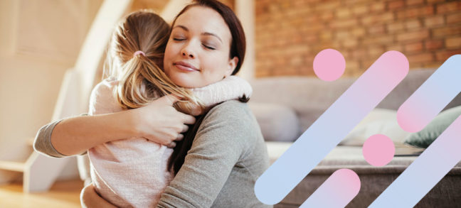 Woman hugs her young daughter inside their home