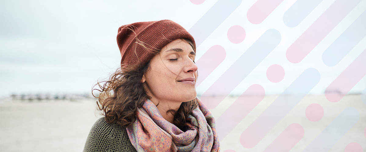 A woman wearing a hat enjoys the breeze on her face