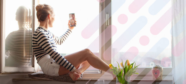 Woman talking on cell phone by window